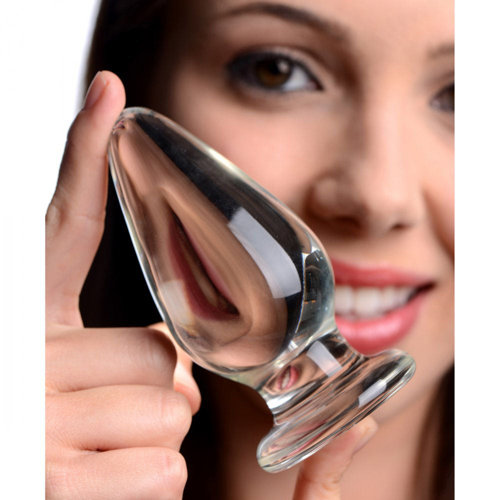 Model holding a clear tapered glass plug near her face for scale.