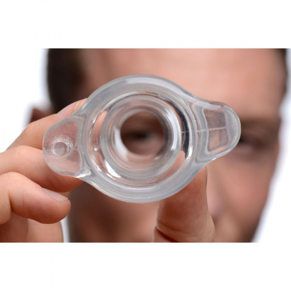 Person holding the clear hollow plug near their face to show the tunnel opening and scale.
