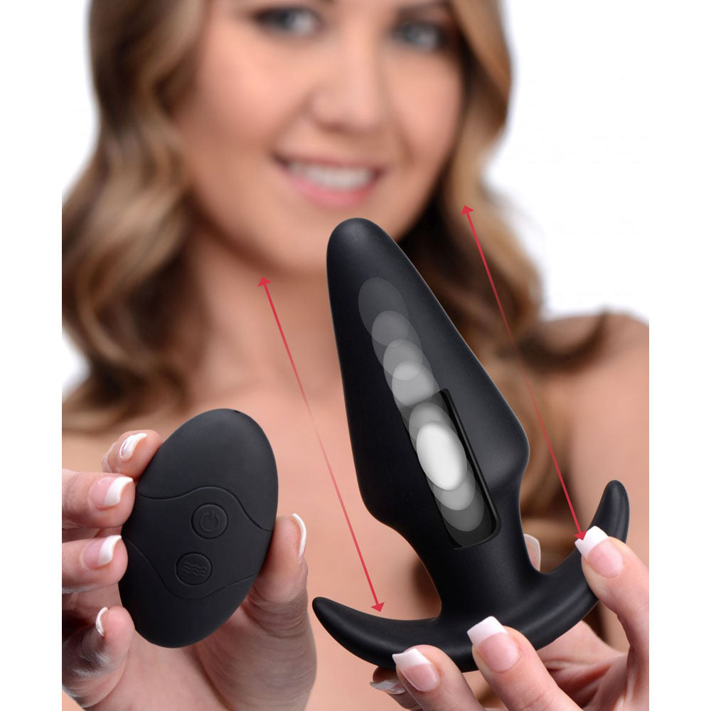 Model holding the black butt plug and remote for scale, with red arrows and internal weight graphic overlay.