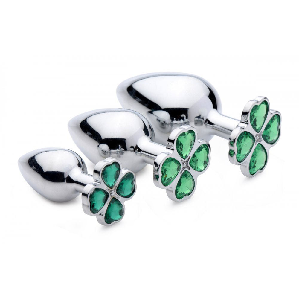 Three graduated metal plugs lined up with green four-leaf clover gem tops.