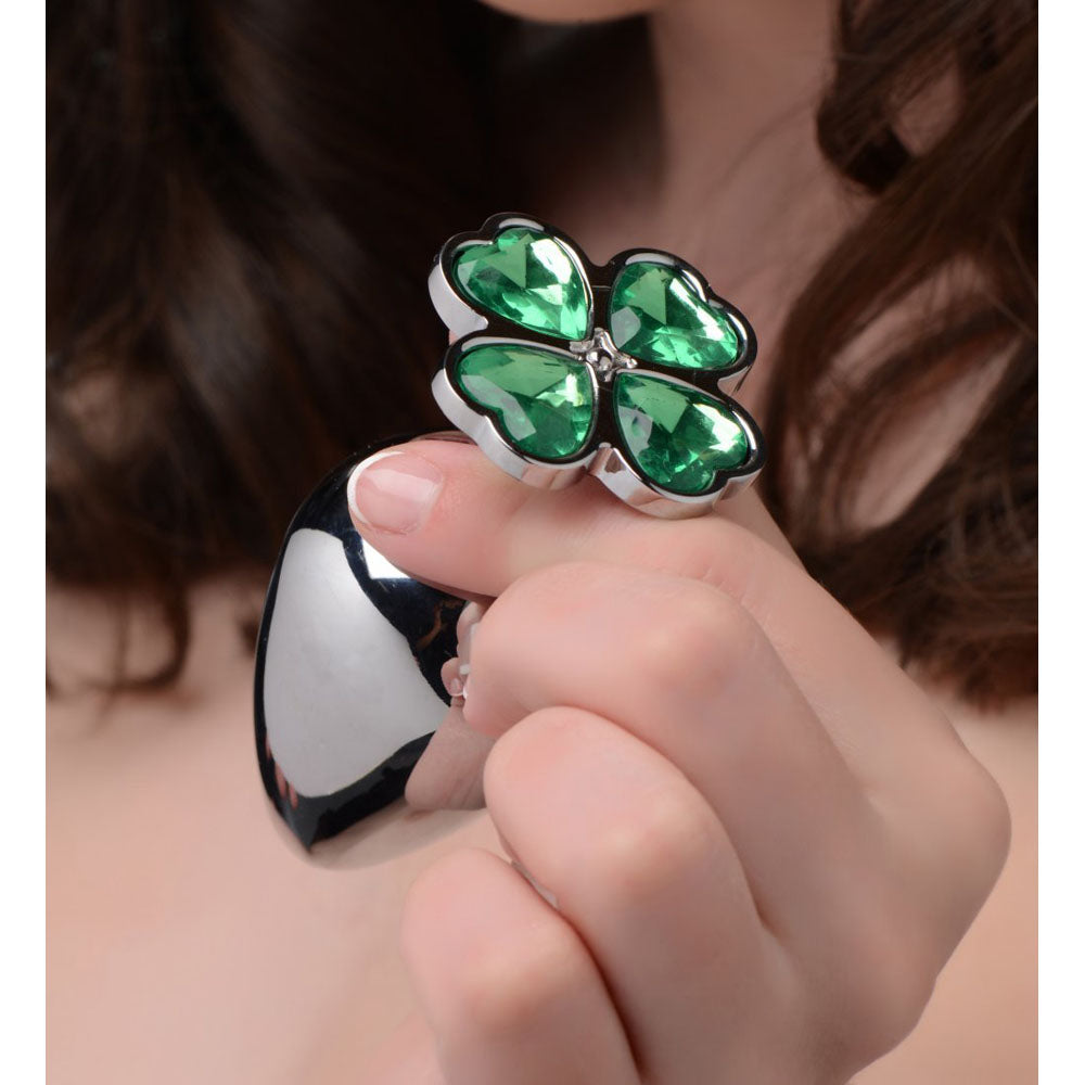Model holding the silver-toned plug near her face to show the green clover gem top and scale.
