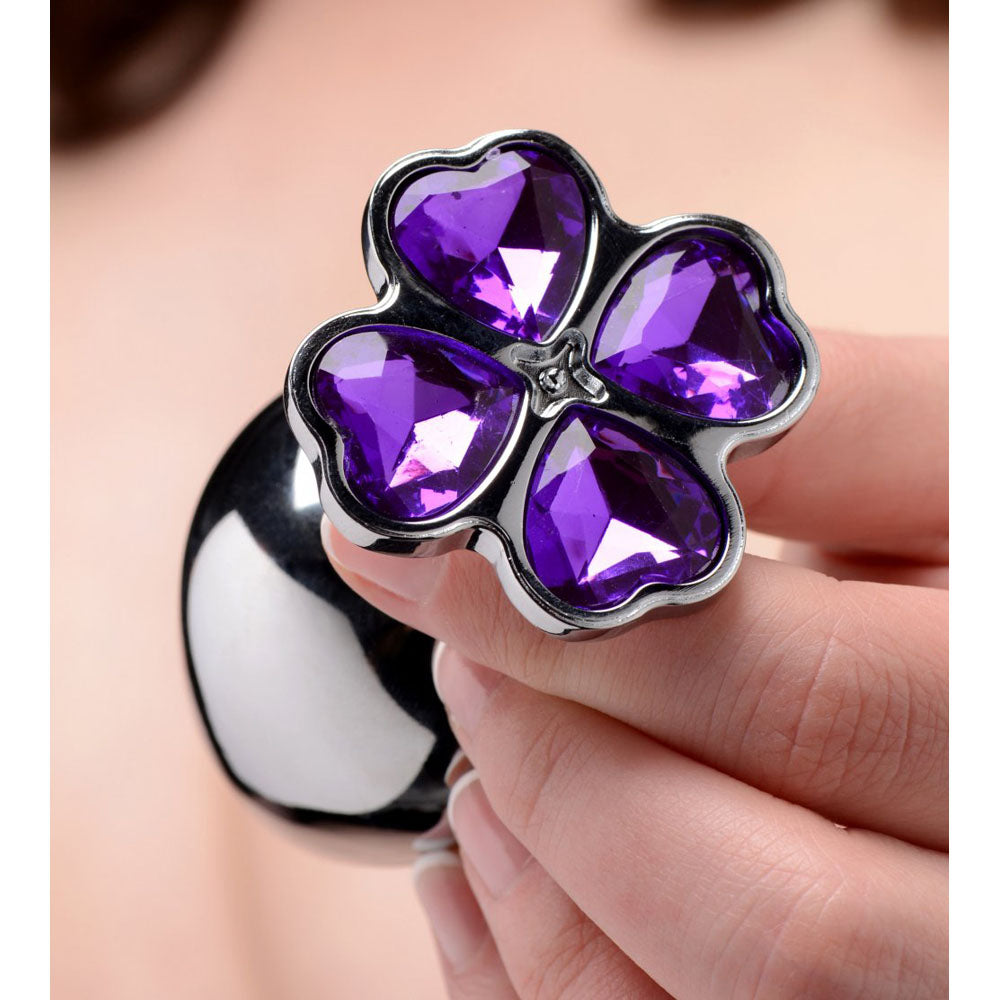 Model holding one polished plug with its purple faceted flower base facing forward for scale.