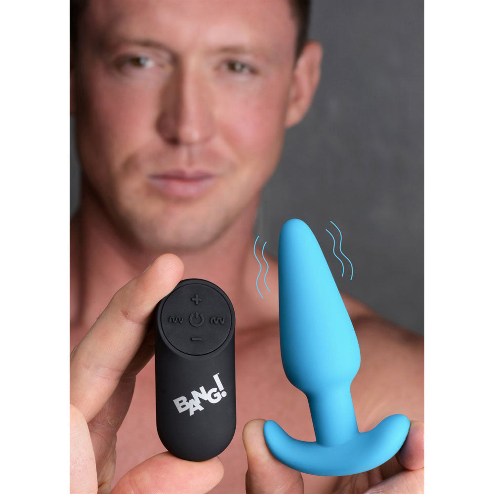 Model holding the black remote beside a blue silicone butt plug with vibration lines.