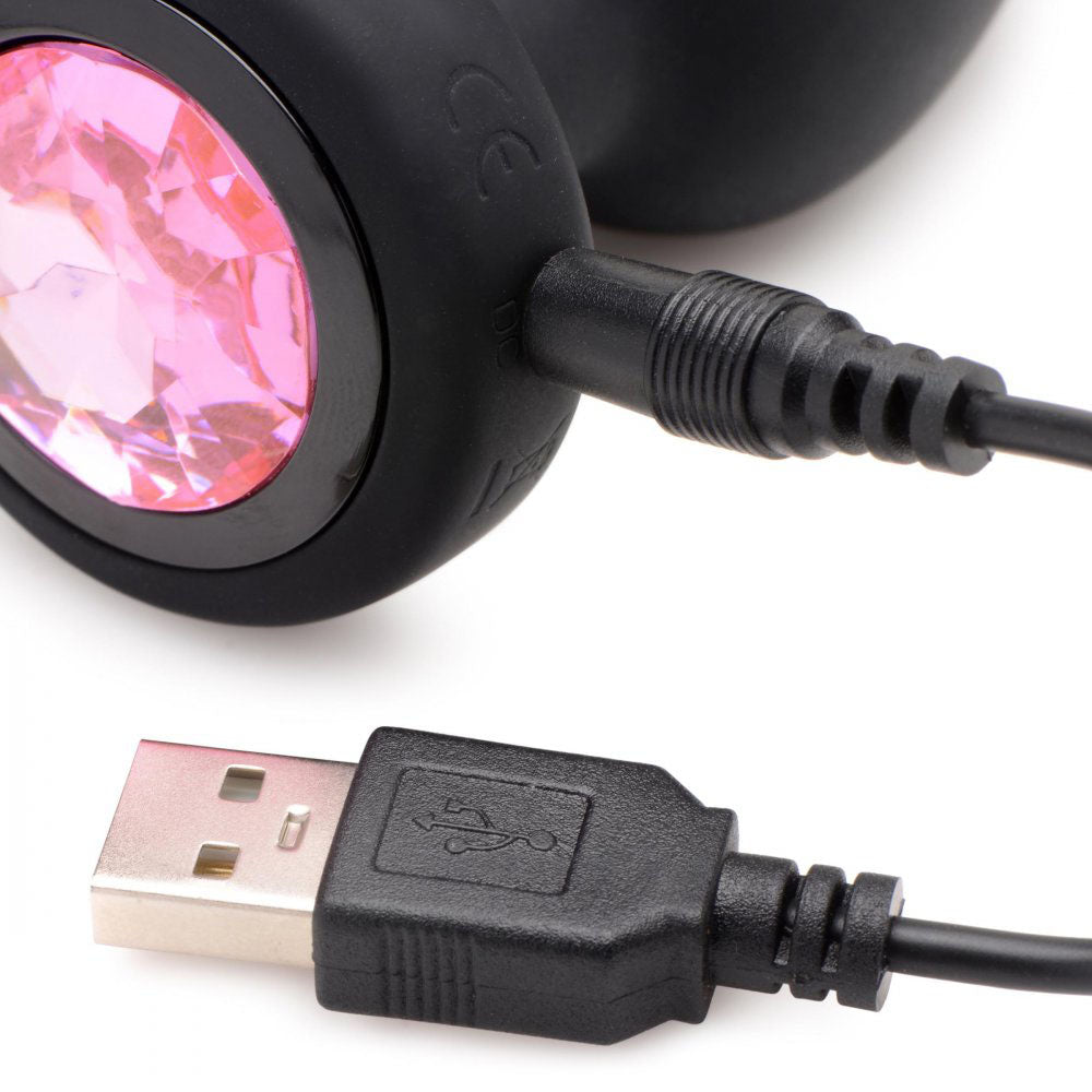Close-up of the pink gem base with the USB charging cable connected to the vibrating plug.