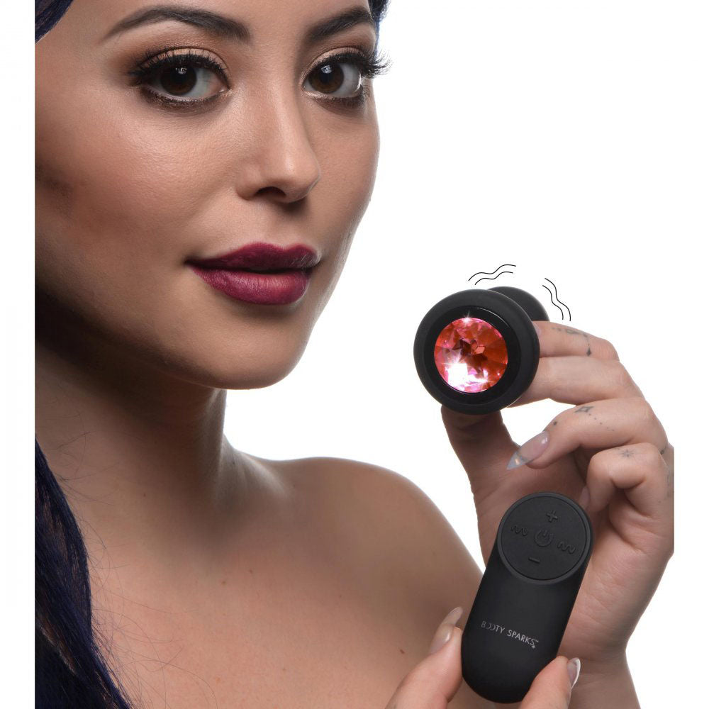 Model holding the Pink Gem Vibrating Silicone Butt Plug With Remote near her face.