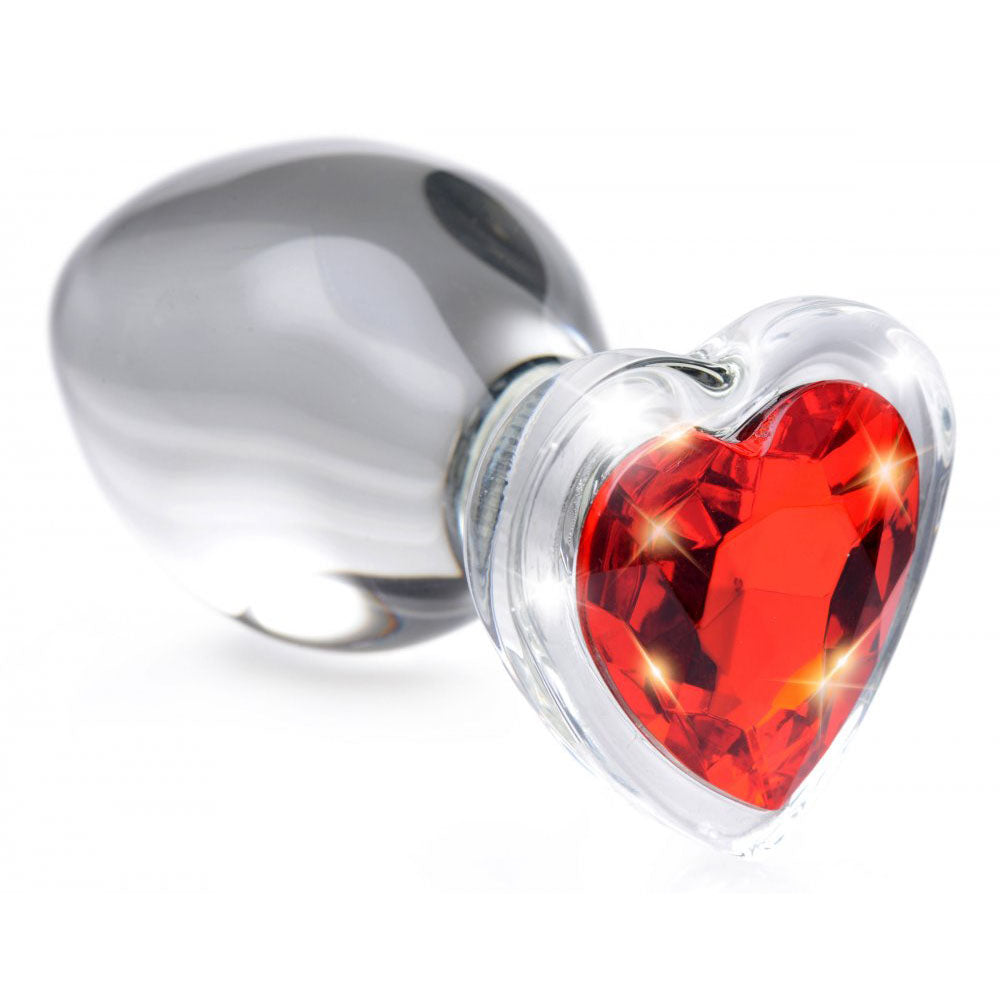 Close-up of the red heart gem base on a clear glass butt plug.