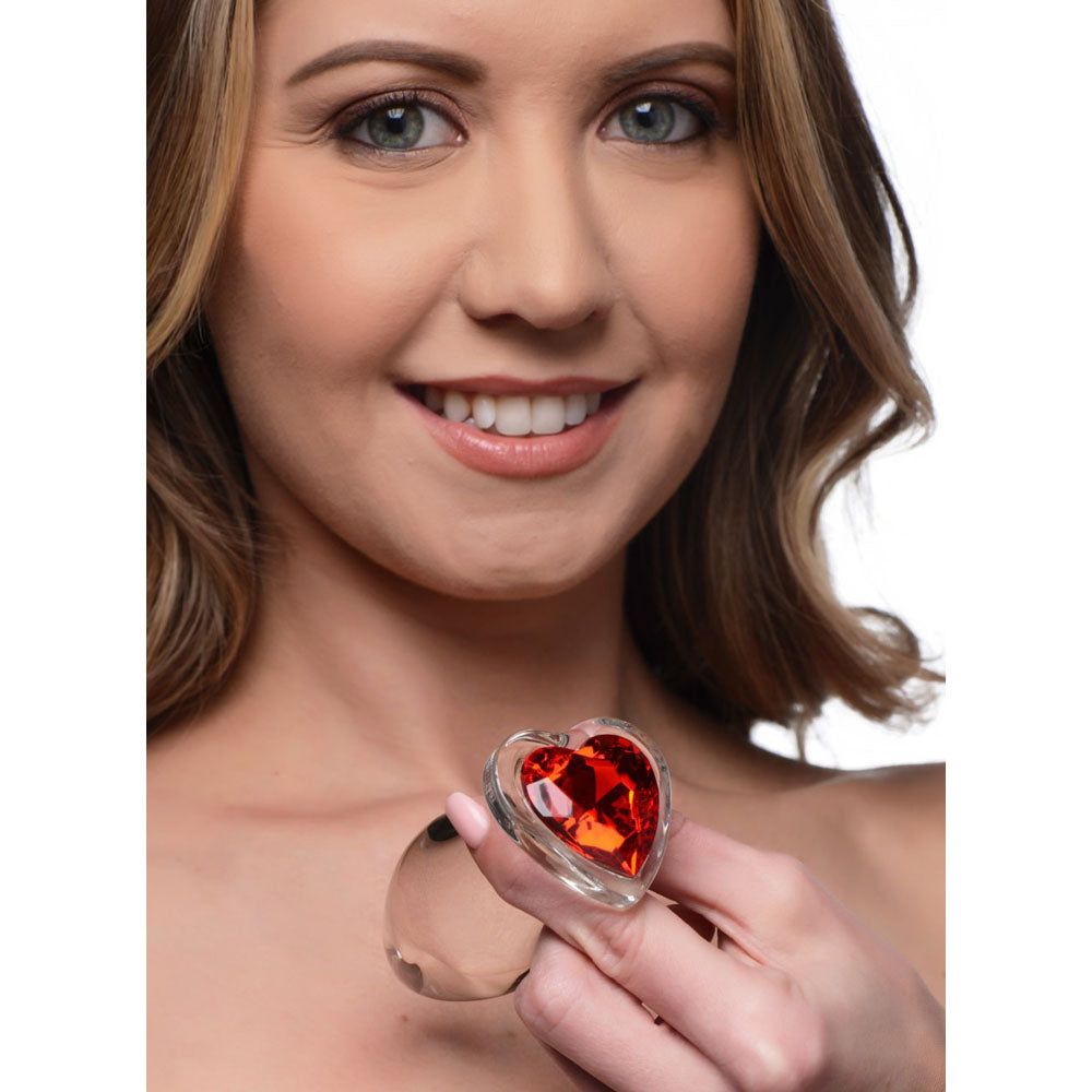 Model holding the clear plug with red heart gem base for scale.