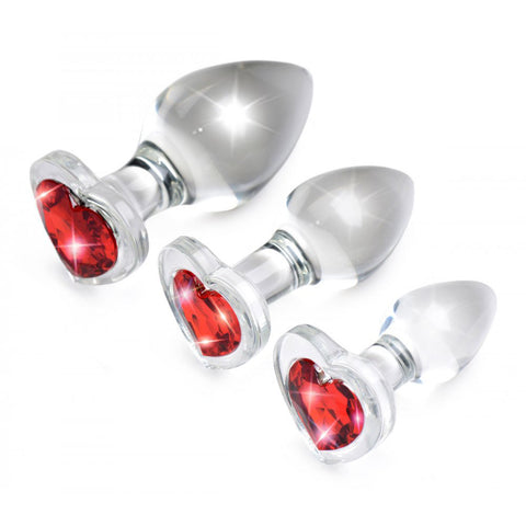 Three graduated clear plugs from the Red Heart Gem Glass Anal Training Set angled to show their faceted red bases.