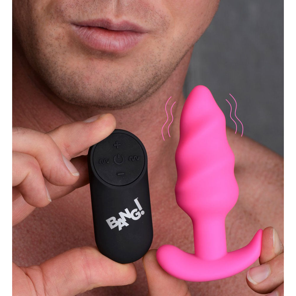 Model holding the pink twisted butt plug and black remote to show scale.