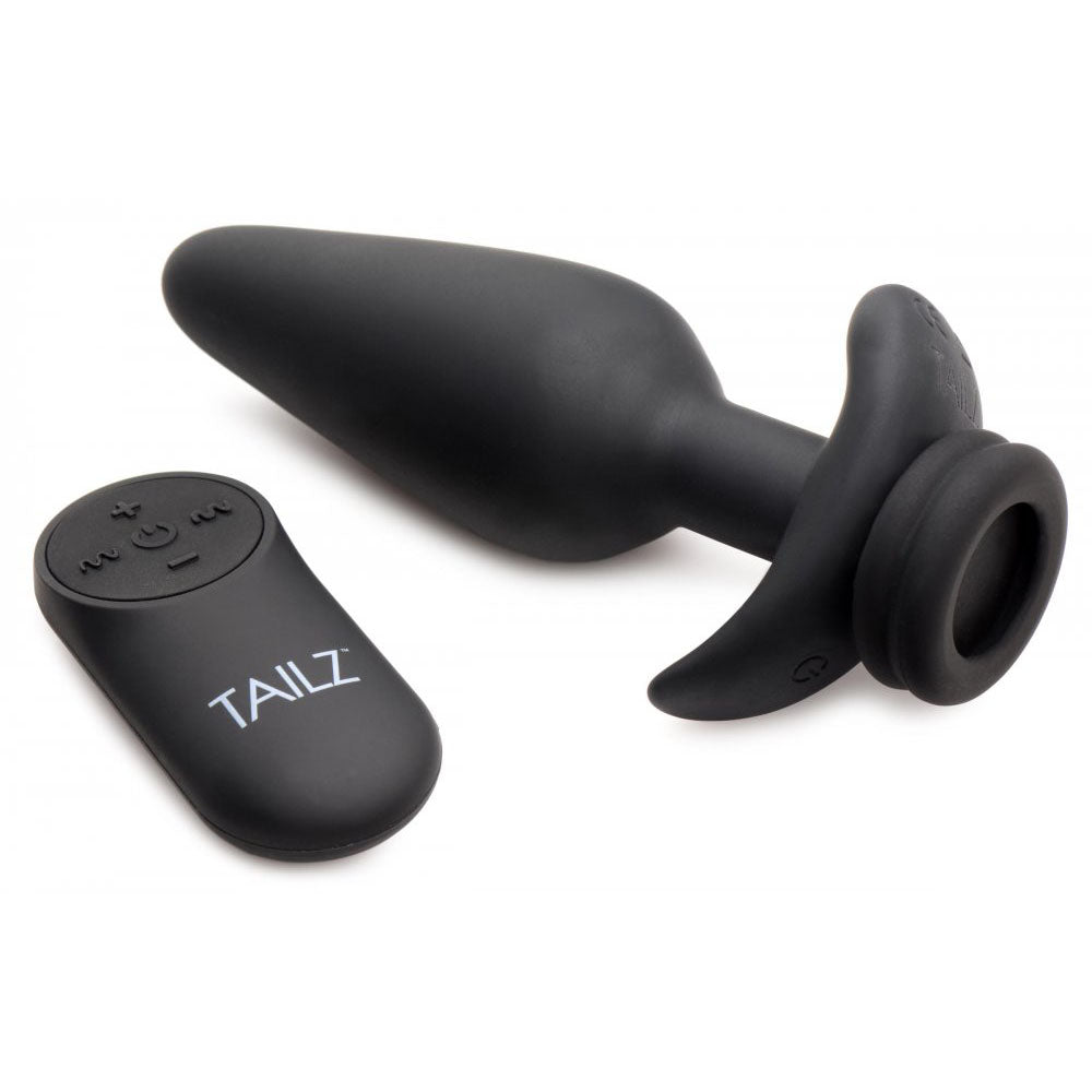 Black plug base lying on its side beside the oval controller, with its curved flared base and circular tail opening visible.